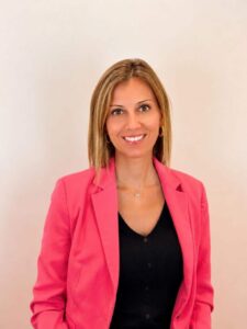 Mujer sonriente con chaqueta rosa en un fondo claro