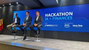 Tres personas sentadas en un escenario durante el hackathon de MoraBanc sobre finanzas e IA.