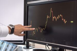 Persona señalando gráfico de tendencias económicas en pantalla