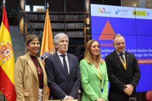 Cuatro personas posan ante banderas y un panel de una reunión iberoamericana.