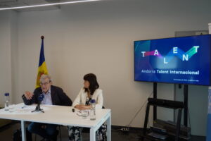 Dos personas sentadas ante una mesa, junto a una pantalla de Andorra Talent Internacional.