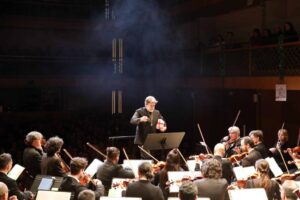 Orquesta en concierto con director y músicos en escena