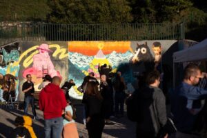 Personas observan murales de grafiti al aire libre durante un festival urbano
