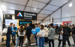 Visitantes se reúnen frente al estand de Grandvalira Resorts en una feria interior.