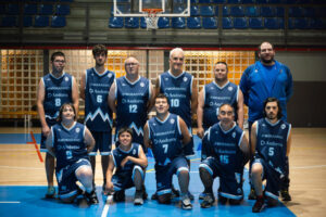 Grupo con camisetas del MoraBanc Andorra posa bajo una canasta en una pista cubierta.