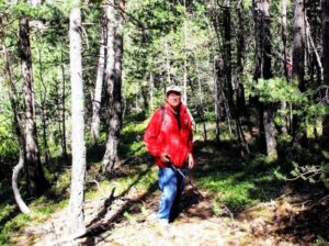 Un hombre con chaqueta roja camina entre árboles por un sendero boscoso.