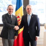 Dos hombres se estrechan la mano delante de la bandera de Andorra