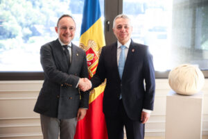Dos hombres se estrechan la mano delante de la bandera de Andorra
