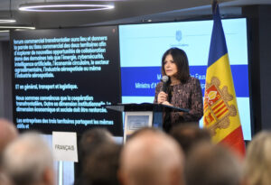 Una mujer habla ante un atril junto a la bandera de Andorra y una pantalla