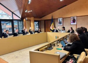 Personas sentadas alrededor de una mesa; algunas levantan la mano durante una sesión.