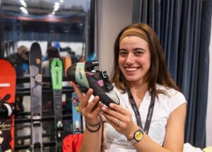 Una mujer sostiene una bota de esquí delante de varios esquís expuestos.
