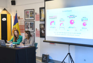 Dos mujeres sentadas ante una mesa mientras se proyecta una diapositiva sobre salud mental.