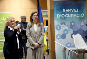 Tres personas en un espacio interior junto a un cartel del Servicio de Empleo