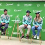 Tres personas sentadas ante un panel verde con logotipos de Creand.